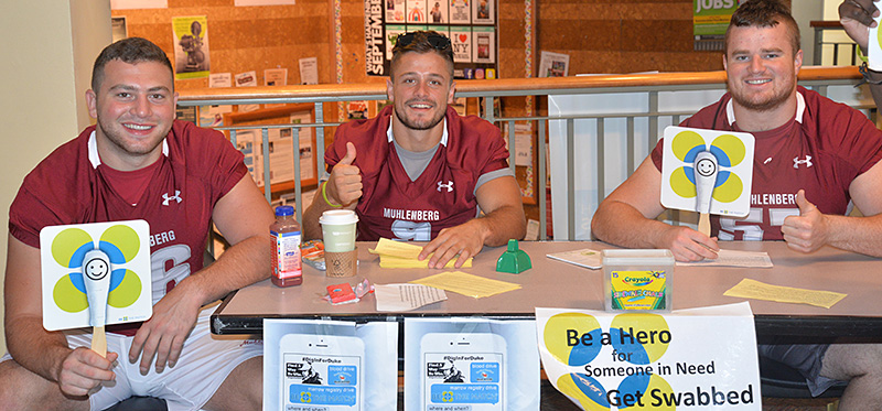 Muhlenberg players urge people to get their cheeks swabbed to see if they are a match for anyone in need on the bone marrow registry.
